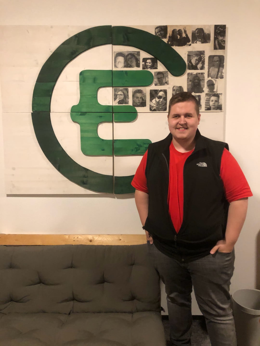 Dennis Müller lächelnd vor großem EC-Logo